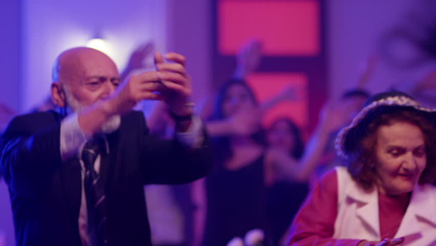 Stylish elderly couple having fun dancing at a colorful party . Sweet senior couple smiling and partying during party . Active retirement . Shot on RED HELIUM Cinema Camera in slow mo Royalty-Free Stock Footage #1024895603