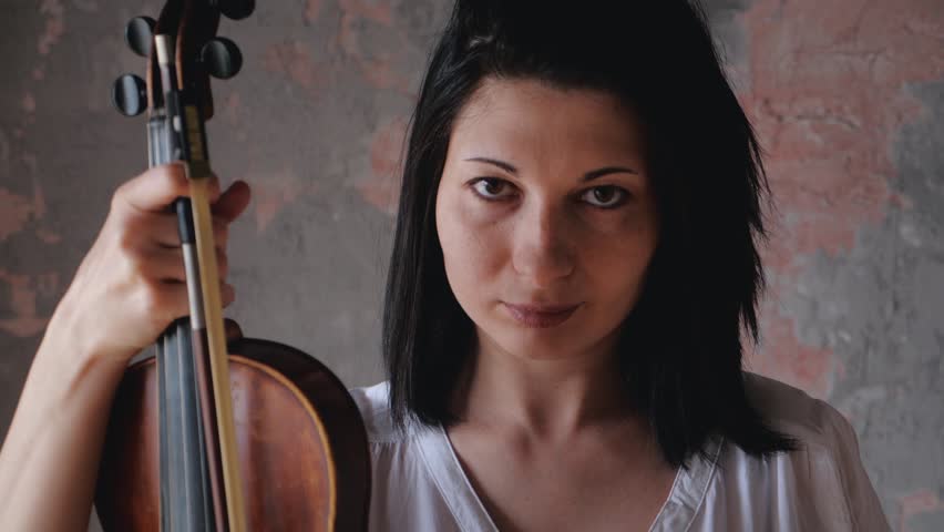 Portrait of female musician holding a violin in her hands and looking at the camera