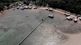Aerial 4k Drone footage of long wooden jetty with Beautiful white sandy beach with turquoise sea water and palm trees at Kuala Abai, Kota Belud, Sabah, Borneo