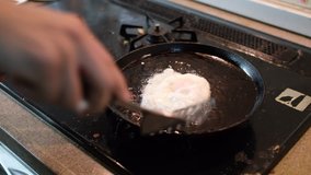 Frying chicken egg on a kitchen stove. Selective focus under low light. 