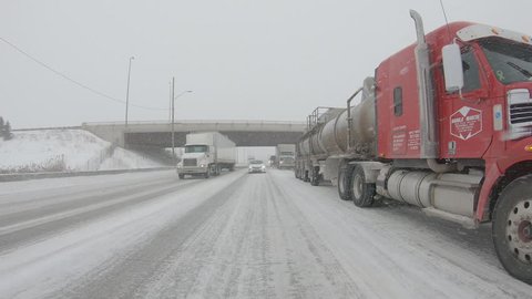 Toronto, Ontario, Canada, February 2019 Trucks, tractor trailers and cars driving highway in snowstorm