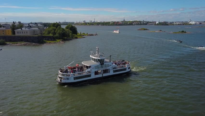 Aerial, pan, drone shot, of a ferry entering Suomenlinna island, on the gulf of Finland, on a sunny, summer day, in Helsinki, Finland