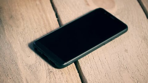 Close up of incoming call to black mobile phone lying on wooden table