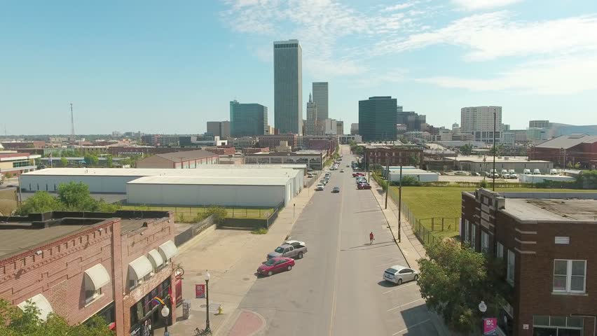 Aerial fly through the built up city of Tulsa Oklahoma, high-rises scattered along the skyline on a bright sunny day.