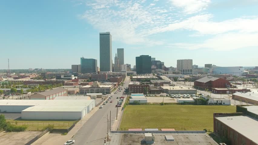 Aerial fly over of the built up city of Tulsa Oklahoma, high-rises scattered along the skyline on a bright sunny day.