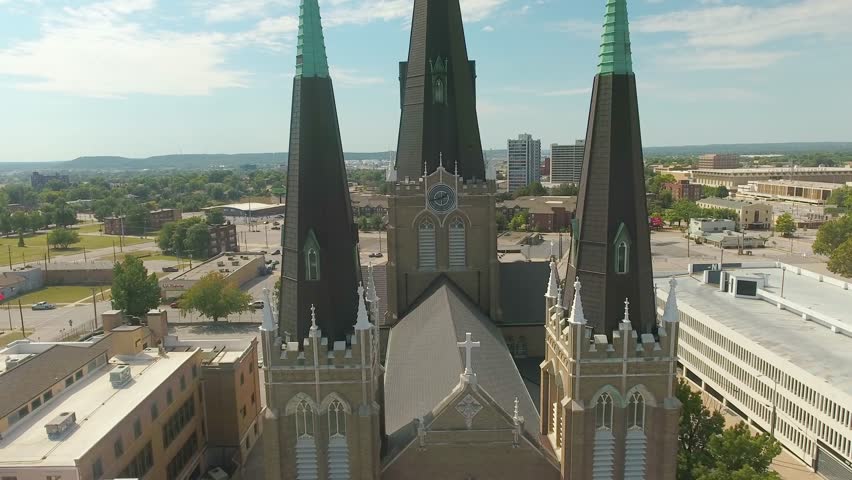 Aerial view moving away from a tall church in Tulsa, Oklahoma on a sunny day.