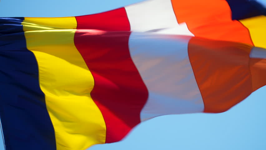 Buddhist flag against blue sky. Slow motion. Colored flag waving in the wind. six colours of the aura of the Buddha