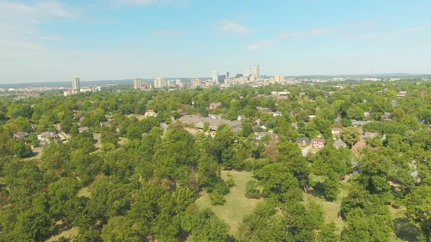 Aerial fly over the residential suburb of Tulsa, Oklahoma with the city skyline on the horizon, on a bright sunny day.