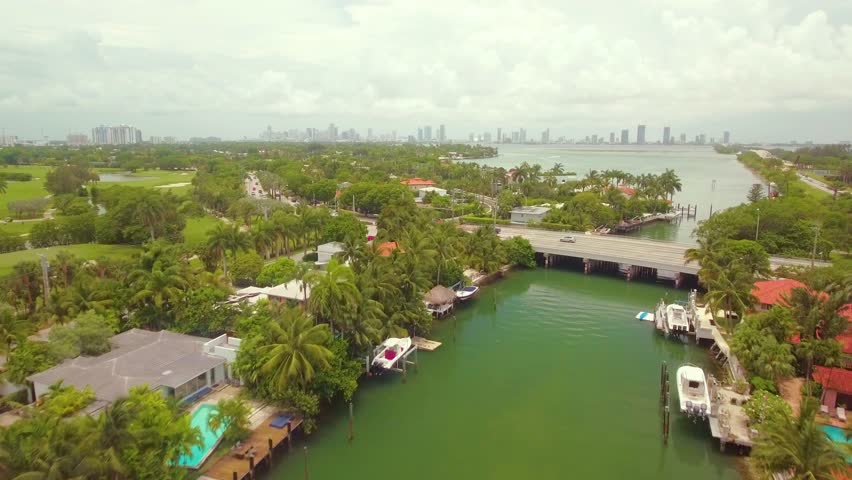 Aerial view over Miami river overlooking a wide road bridge with the cityscape in the background.