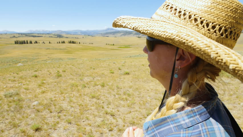 Woman in cowboy hat looks out over high country of Yellowstone National Park