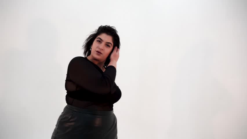 Slow motion of pretty plus size model and flying in air dress looking at camera