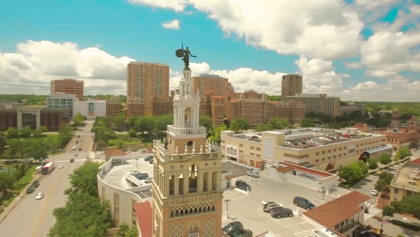 Wide aerial 360 degree orbit shot of the Kansas City skyline, high-rise buildings and statue on the Country Club Plaza tower.
