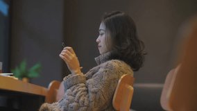 Side view of one pretty young Asian woman playing with mobile phone in the cafe by the window, Beautiful Chinese girl with mobile technology lifestyle in the city 4k clip