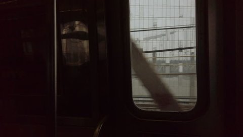 Looking out the window of a New York City subway train in motion going over the Manhattan Bridge. Cinematic, dark, gritty, hand-held POV shot.