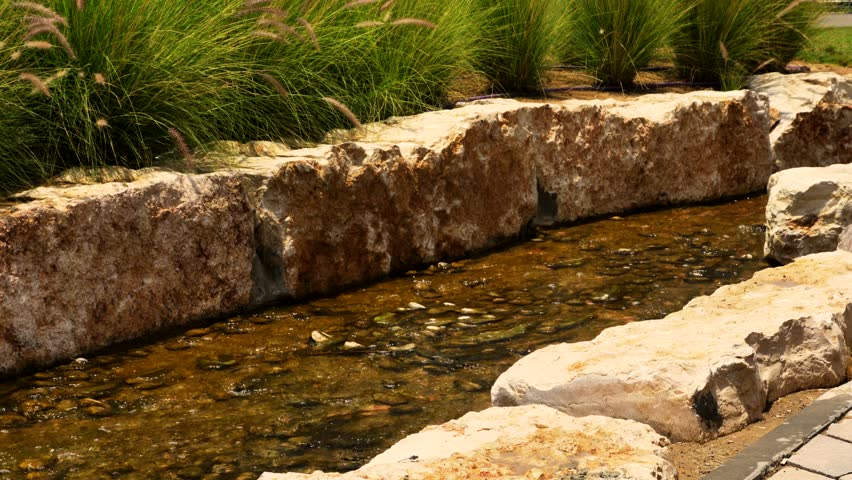 Decorative stream with stone fences in the park. 4K