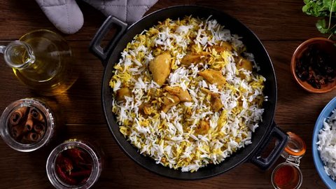 Biryani with chicken. Traditional Indian dish of rice and chicken marinated in spices and yoghurt.Sprinkling with fried onions. Slow motion.