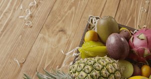 Juicy pineapple, dragon fruit, passion, kiwi in a box on a wooden background. Top view. Panoramic motion, 4K UHD video, 3840, 2160p. Top view.