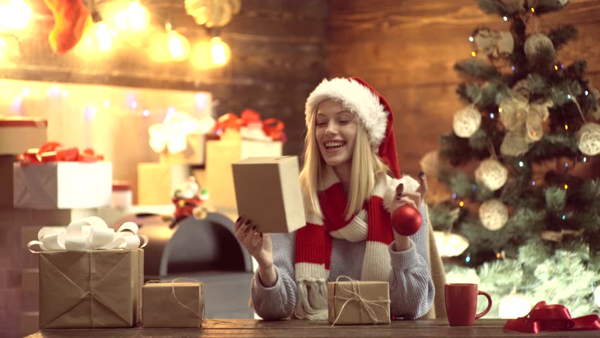 Happy young lady gifts by the fireplace near the Christmas tree. New year concept. Christmas tree, presents and gift boxes under it. New Year decorations. New year woman