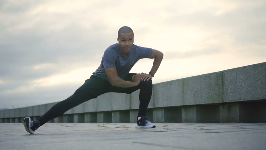 Happy adul african american beautiful and professional sportsman doing exercise and activity for his health in the city in slow motion. Black young and attractive man bodybuilder lifting running and