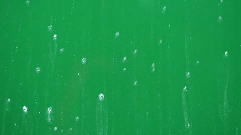 Rain drops on glass, bubbles .  Green screen backround. Chroma key. 4K -UltraHD