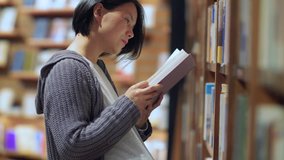 Side view of one pregnant Asian woman reading book in the library. pregnant female urban lifestyle 4k clip. concept of education  