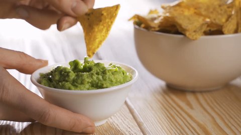 Person eating guacamole while scooping a chip