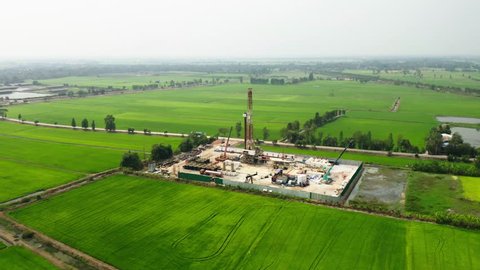 Oil and gas a land rig, onshore drilling rig, in the middle of a rice field aerial view from a drone
