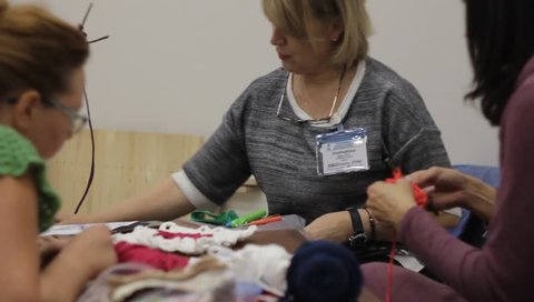 Odessa,Ukraine - December 22 2018:  Woman teacher  conducts the women a masterclass on crochet lace or clothing. Taken from a moving camera on a slider. Camera dolly



