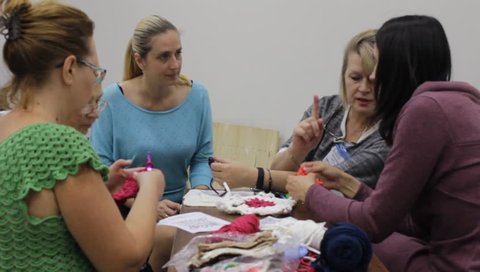 Odessa,Ukraine - December 22 2018:  Woman teacher  conducts the women a masterclass on crochet lace or clothing. Taken from a moving camera on a slider. Camera dolly



