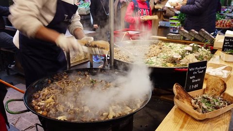 BOROUGH MARKET, LONDON - JANUARY 10, 2019: A chef cooks wild mushroom risotto in a large frying pan at Borough Market in Southwark, London, UK.