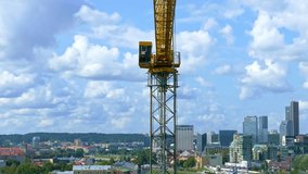 Crane operator sits in the cab of the tower crane on the background of the aerial panorama of Vilnius, Lithuania.