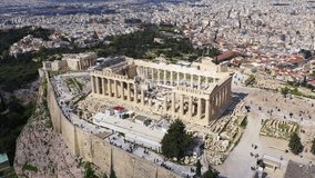 Aerial drone bird's eye view rotational video of iconic Acropolis hill and the Parthenon with beautiful scattered clouds, Athens historic center, Attica, Greece