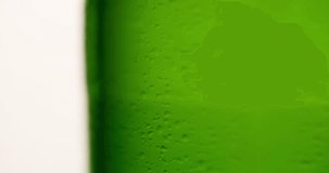 Wet Green Beer Bottle rotating with flowing droplet Closeup macro Slow motion Advertising shot on white background 4K video