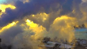 Breathtaking sunrise breaking through heavy factory smokestack emissions in cold Winter air, aerial view.