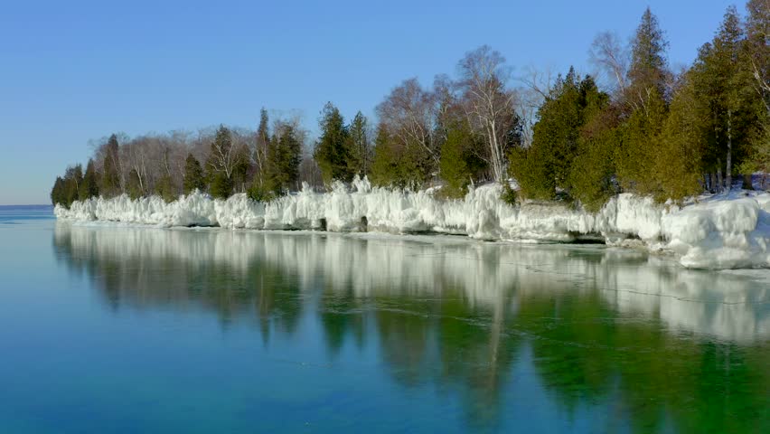 Scenic Rocky Wisconsin Wilderness shoreline with evergreen trees encased in thick ice.
