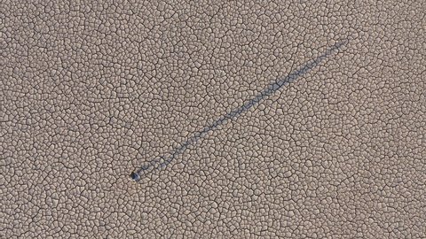 Climate change.Climate emergency.Epic aerial view of a devastated farmer walking across the cracked mud surface of a dry dam due to drought from climate change and global warming