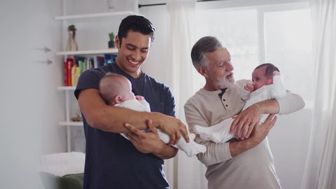 Young Hispanic man and his senior father holding his two baby boys at home, close up