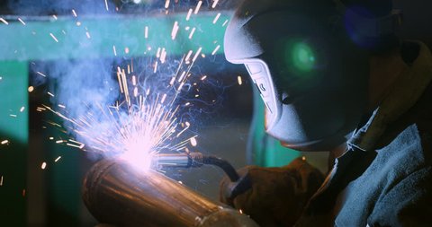 Welder. Industry. Work at the factory. Pipe welding. Electrode. Melting. Welding works. Semi-automatic welding. Gas welding. Slow-motion. High quality 4k video. Shot with RED camera.