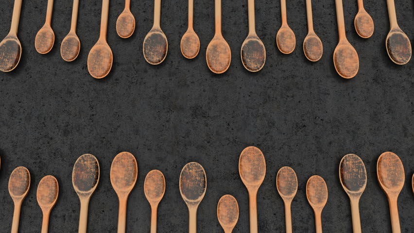 vintage wooden spoons laid out in a row are moving horizontally in front of the camera