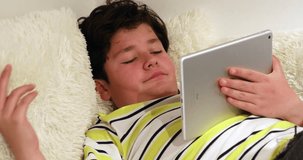 Portrait of a sleepy teenage boy with digital tablet computer lying on sofa and sleeping