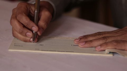Man filling anount and signing a cheque