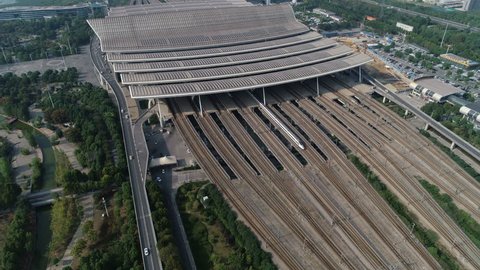 Tilting drone footage of an arriving and departing bullet train at the modern high-speed railway station in Wuhan, China