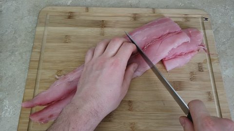 Home cooking - Placing skinless and bone less Mahi-mahi fish filet on wooden cutting board and slicing it into small portions or pieces readying for cooking.