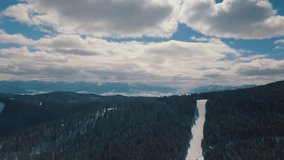 Aerial drone footage of winter ski park in Carpathian mountains.Popular winter resort for active tourism shot with flying video camera in cold season.Ski,snowboard tracks & ski lifts in forest 