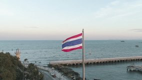 SLOW MOTION of the Thailand national flag flying high with the ocean in the background in Pattaya Thailand