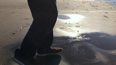 Man testing beach for quicksand danger by cautiously stepping on it