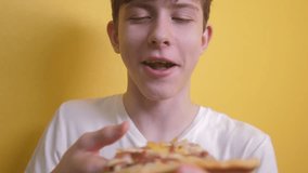 happy teen boy eating a slice of pizza concept. teenager boy hungry eats a slice of pizza. slow motion video. lifestyle pizza fast food concept