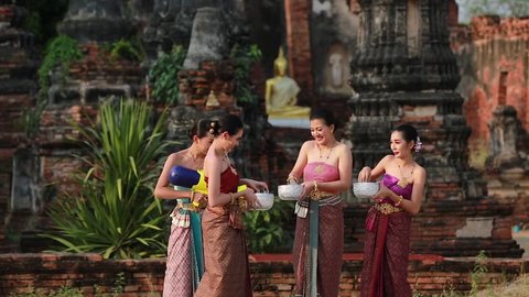 Thai women in Thai national costumes are playing splashing water on Songkran day. Which is one of the important traditions of Thailand which is the Thai New Year's Day
