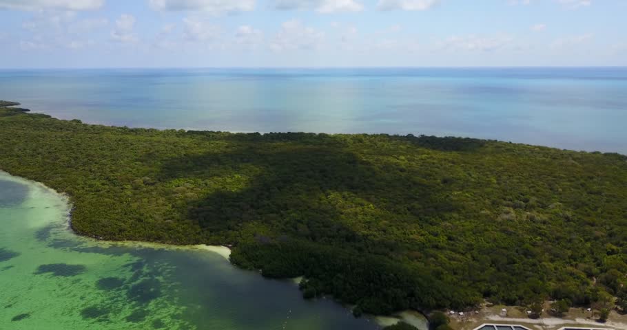AERIAL: pulling away and tilting down to both hide and reveal the dock and shoreline of Elliot Key, Florida.