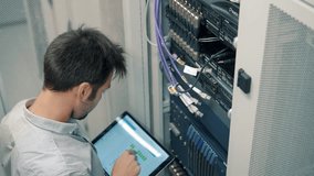 It Technician Engineer With Tablet Work In Server Room In Data Center.  Male IT Engineer Working In Data Center With Rows Of Server Racks And Super Computers, Into Data Cabinets. ISP Hosting Support - Powered by Shutterstock - Get 15% off with code: PIKWIZARD15